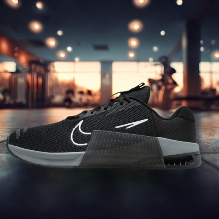 Black Nike Metcon 9 training shoe with a sturdy midsole and white swoosh, shown on a gym floor, ideal for hybrid training