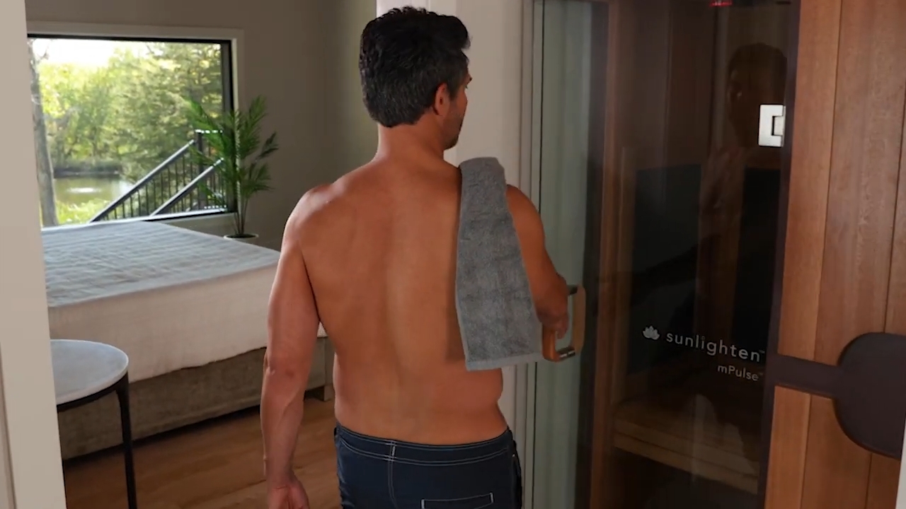 Man with a towel enters an infrared sauna in a quiet home room